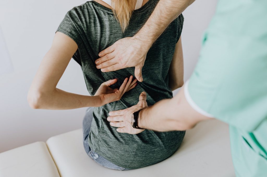 A woman with back pain having chiropractic treatment