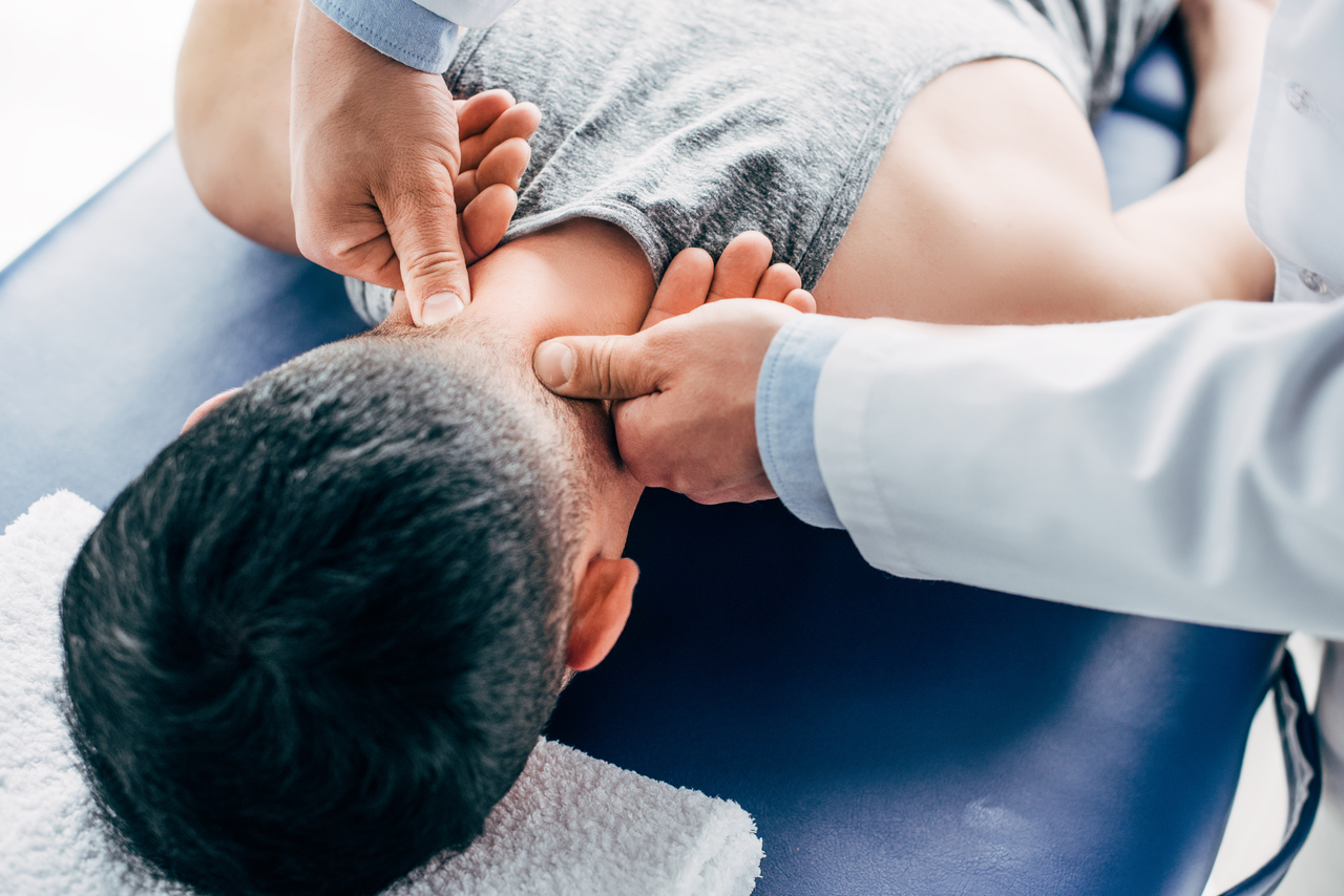 chiropractor massaging neck of man