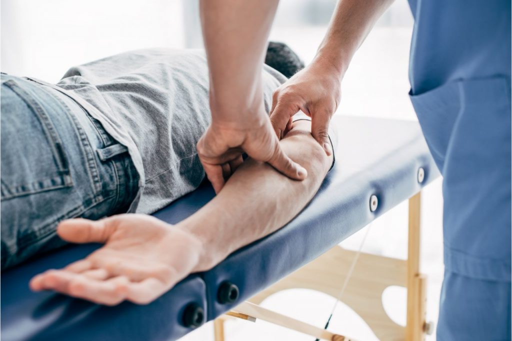 Chiropractor massaging a man's elbow