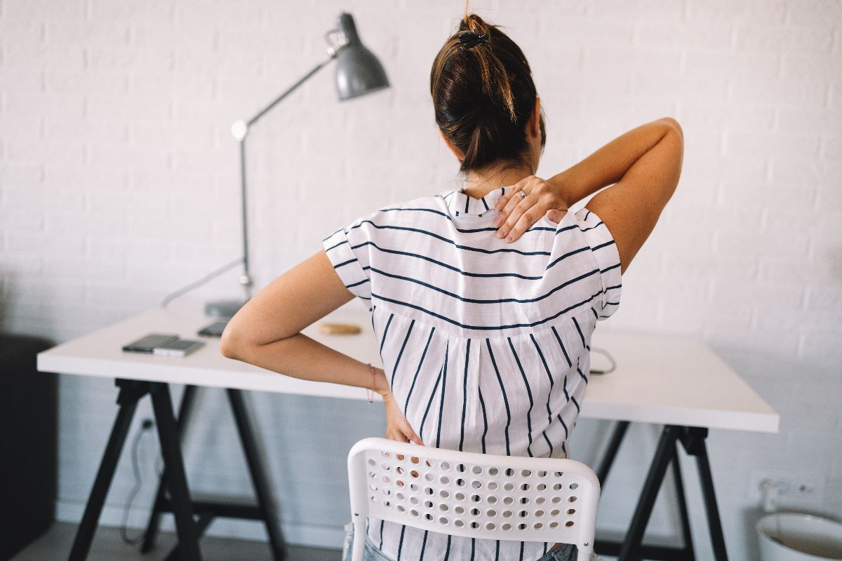 A woman stressed with the back pain she's experiencing while working