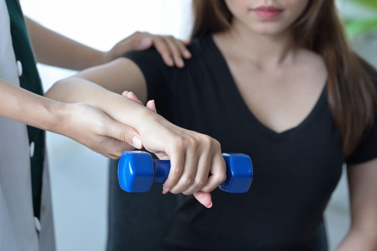 Patient performing a dumbbell rehabilitation exercise with therapist support
